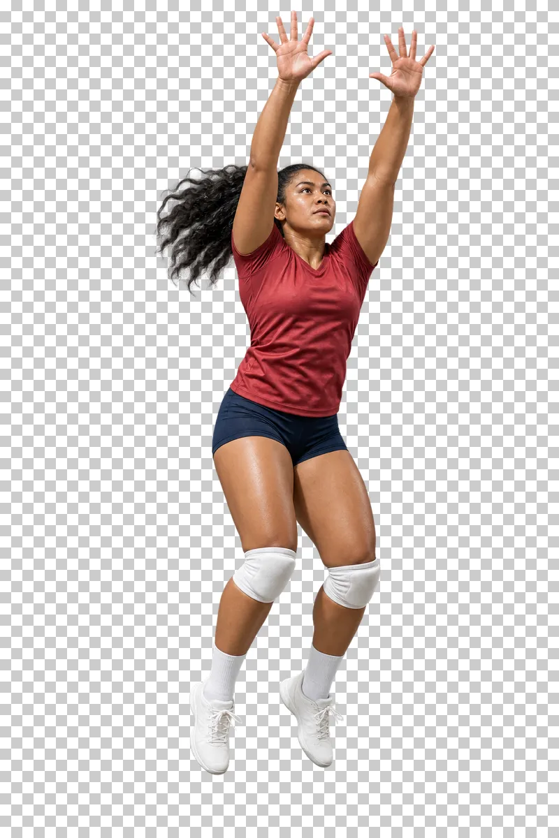 A woman in a muted red top and navy shorts jumping with both hands raised for a volleyball block.