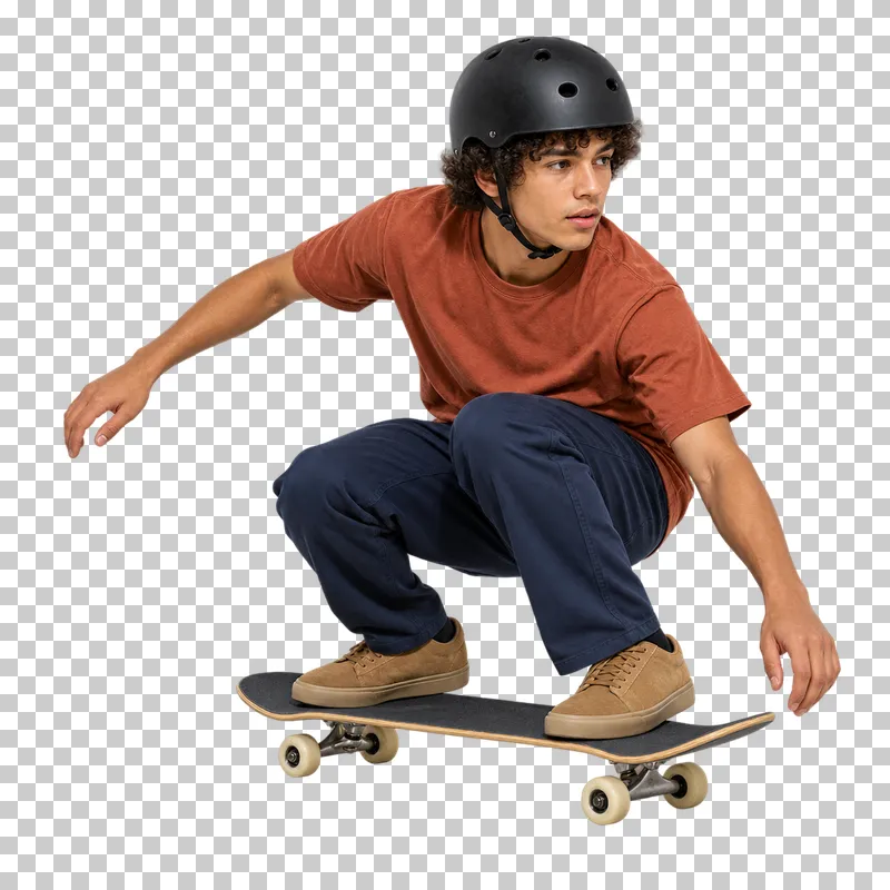 A young man in a rust T-shirt and navy trousers crouching on a skateboard.