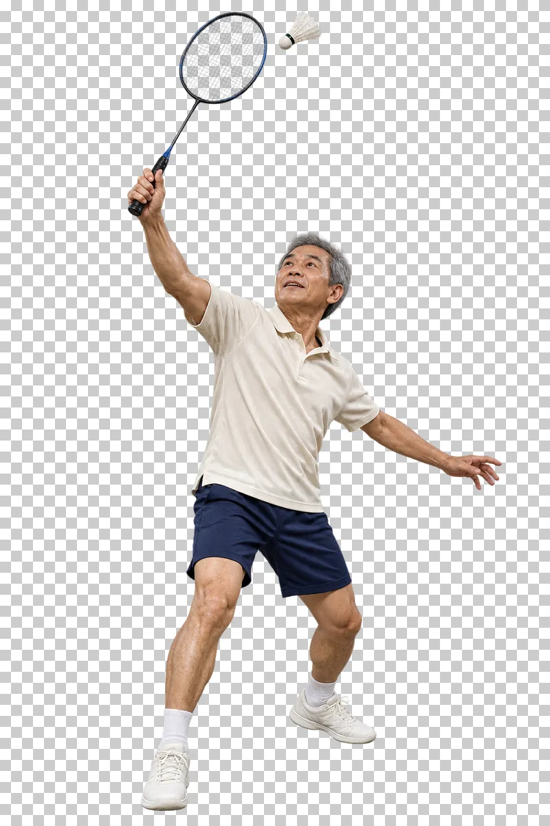 An older man in a cream polo and navy shorts raising a badminton racket toward a shuttlecock.