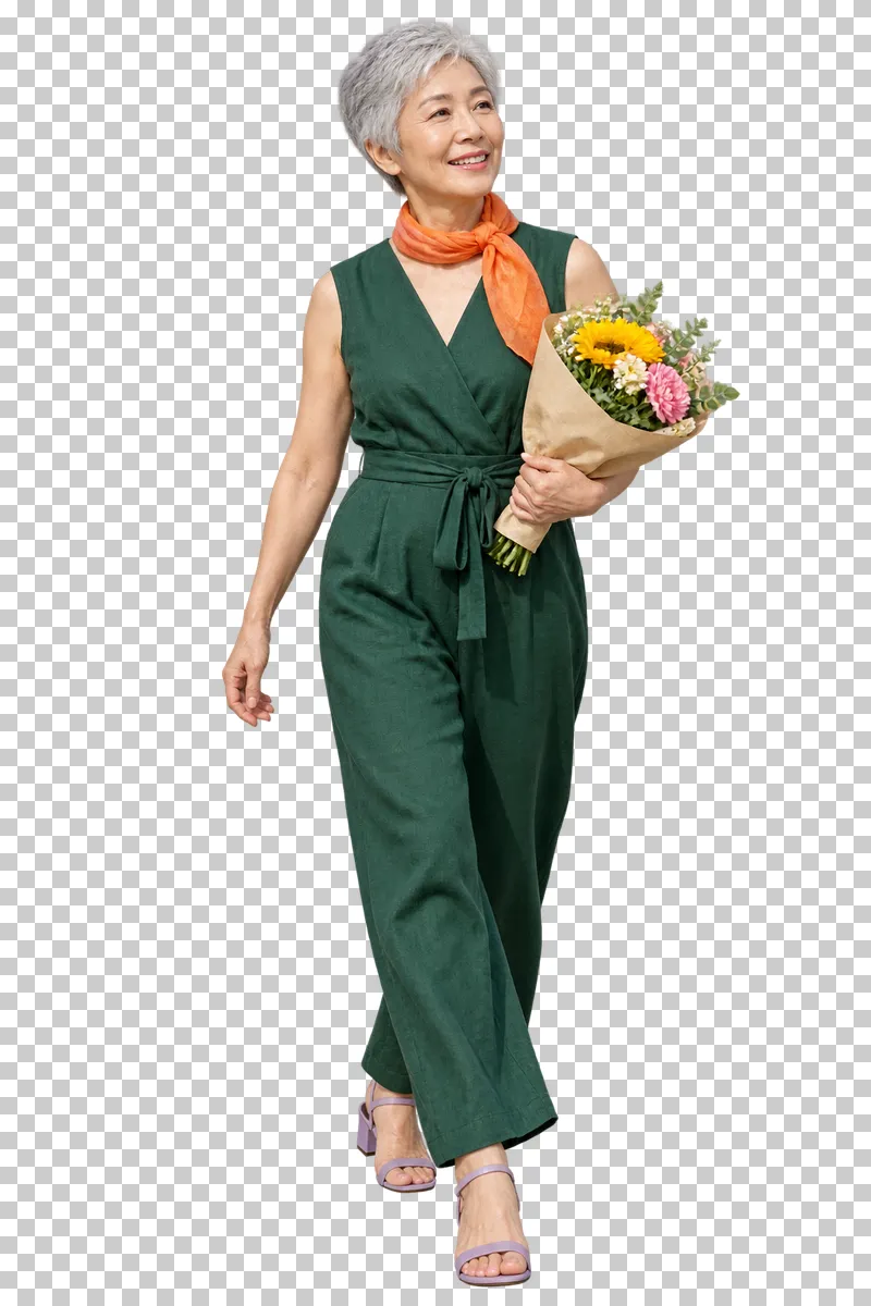 A silver-haired woman in a green jumpsuit and orange scarf carrying a bouquet of yellow and pink flowers.