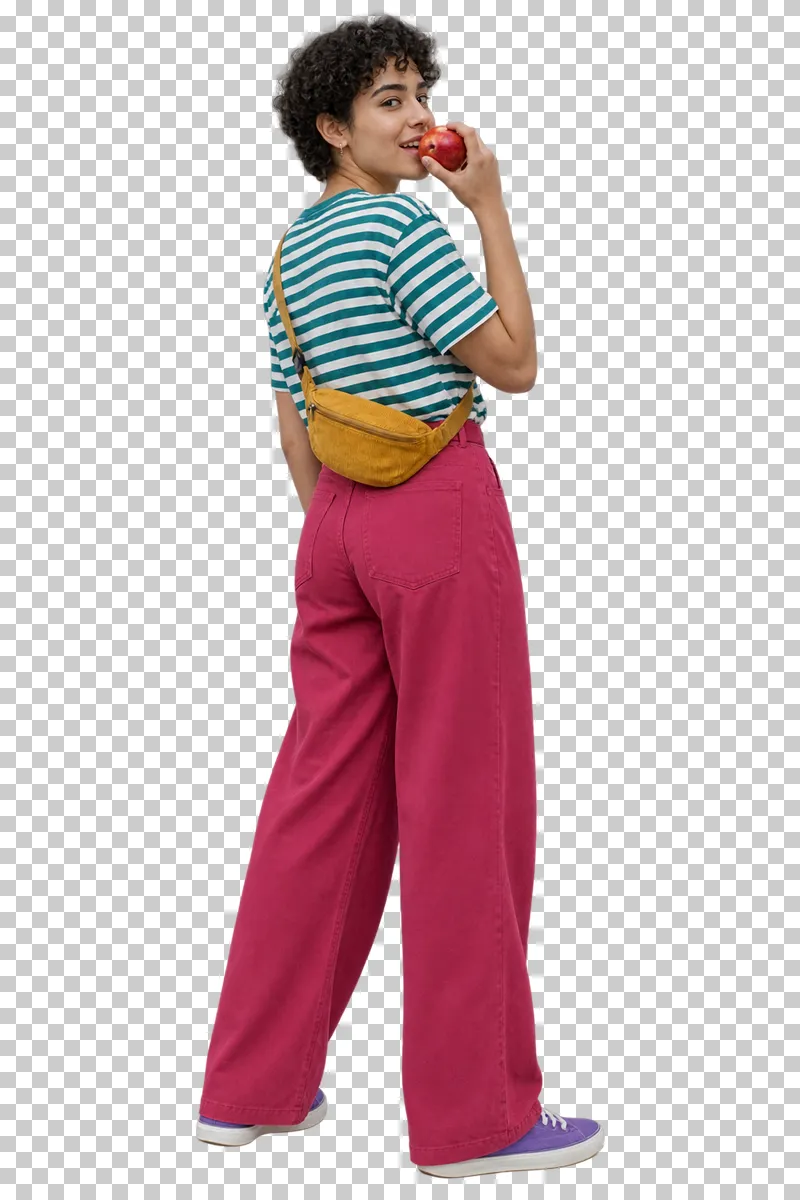 A young adult in a teal striped shirt and raspberry trousers eating an apple.