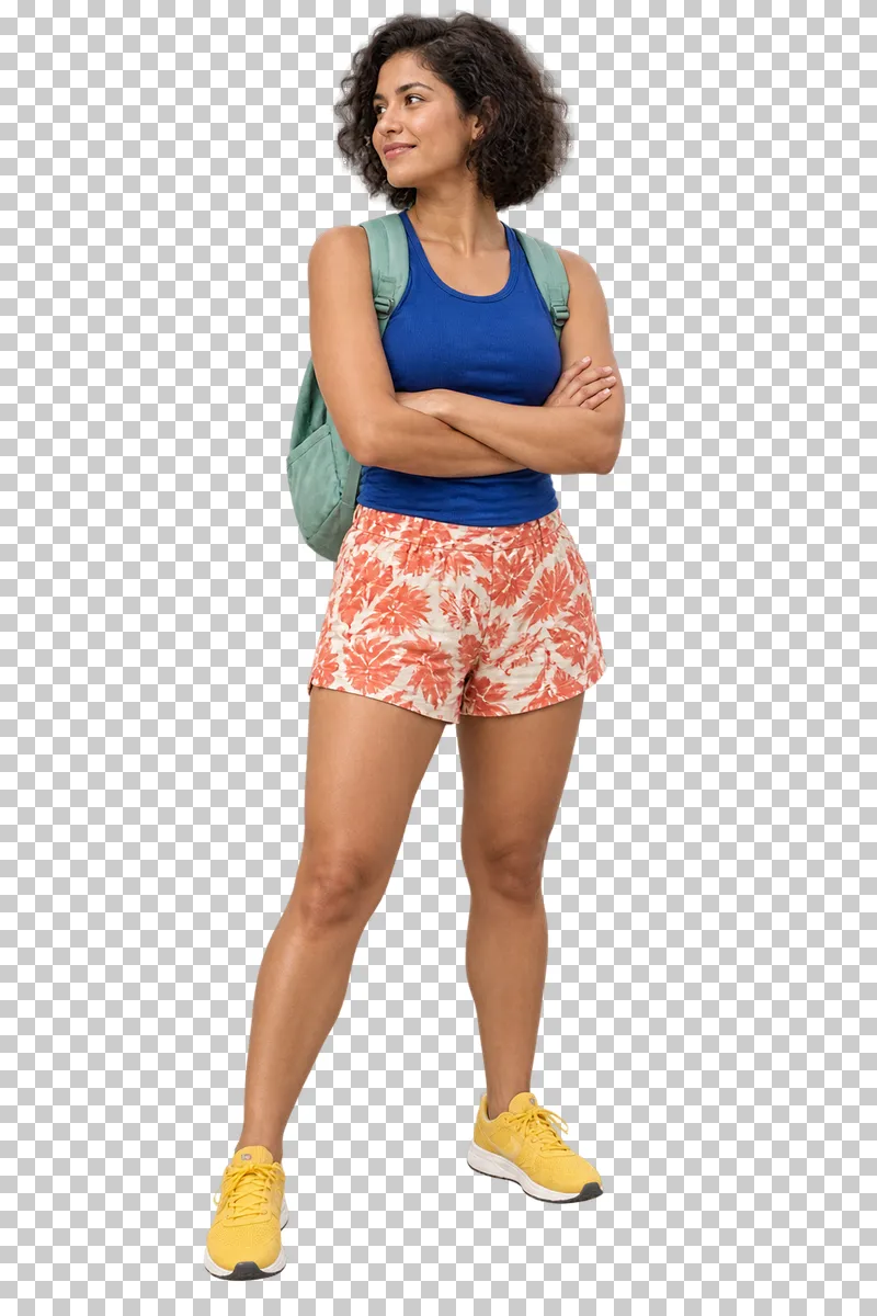 A woman in a cobalt sleeveless top and coral patterned shorts standing with her arms folded.