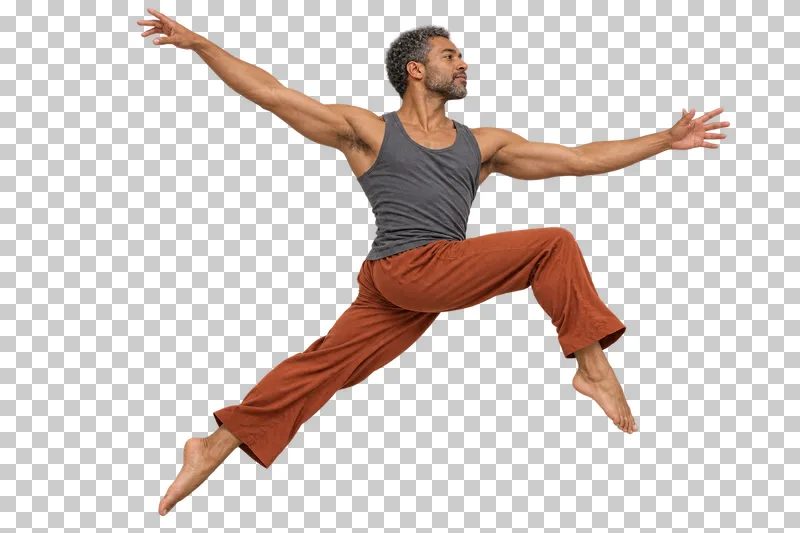 Male contemporary dancer in a slate top and rust trousers performing a small stag jump.