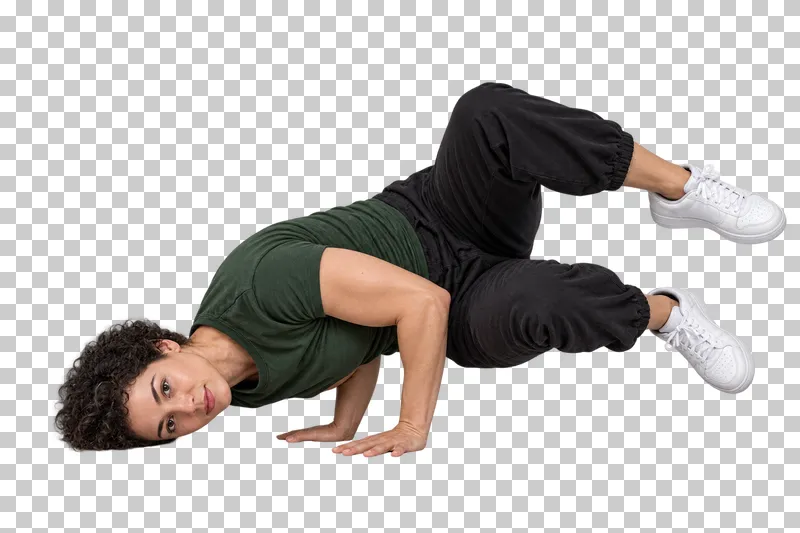 Breaking dancer in a green T-shirt and black joggers holding a compact baby freeze with bent knees.