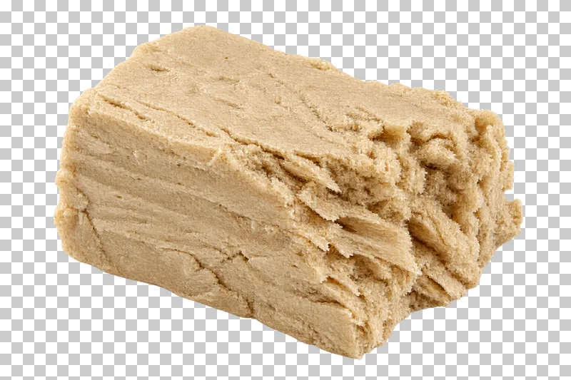 A plain sesame halva fragment with fibrous layers and a crumbly broken face.