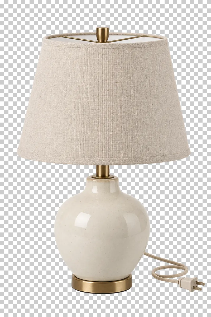 An unlit ceramic table lamp with linen shade with its complete fixture isolated on a transparent background.