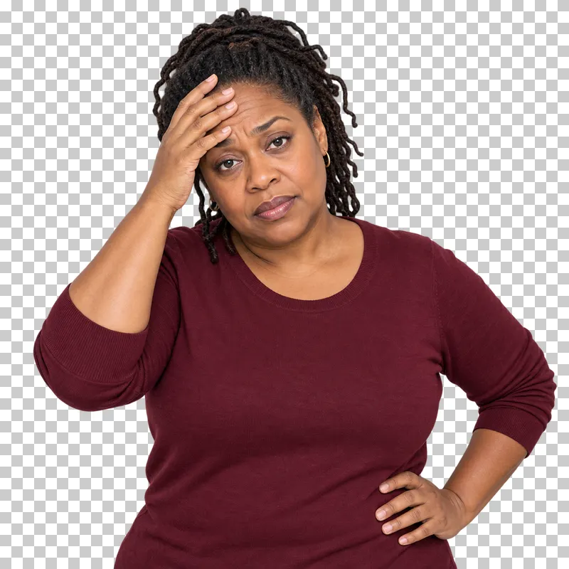 A woman with tied-back locs in a burgundy pullover resting a hand on her forehead in fatigue.