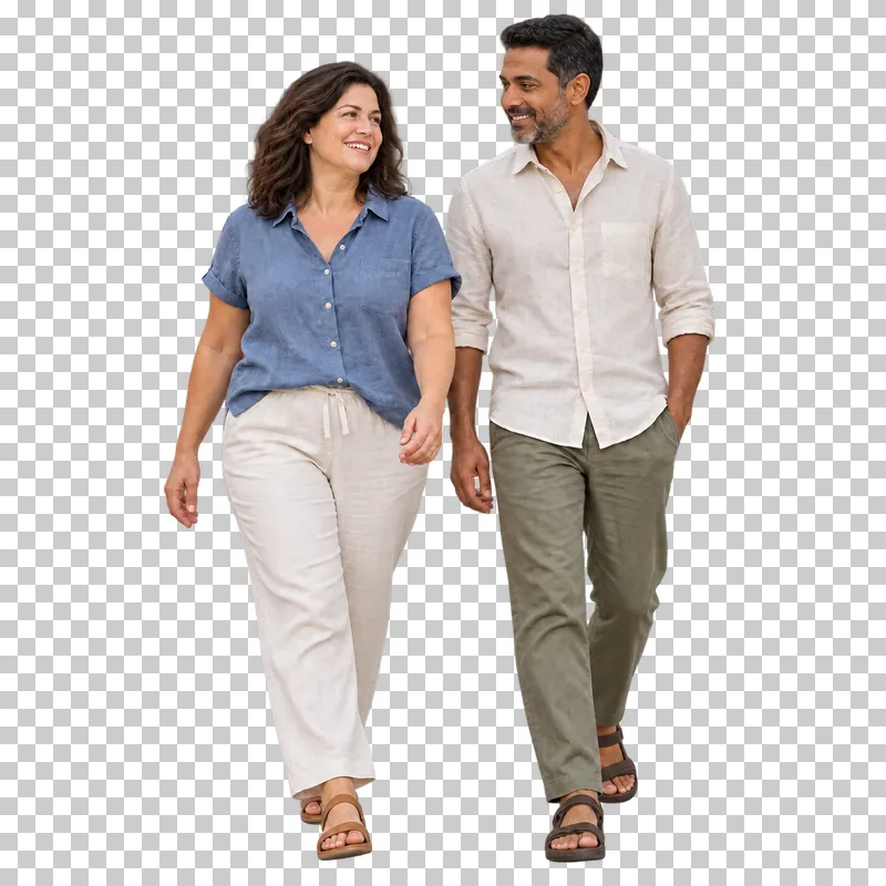 An adult couple walking side by side in linen clothing and sandals.