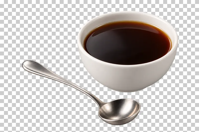 A handleless white coffee cupping bowl filled with brewed coffee beside a stainless tasting spoon.