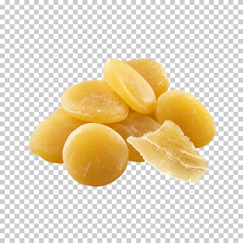 Honey-yellow beeswax pastilles beside one thin irregular wax flake.