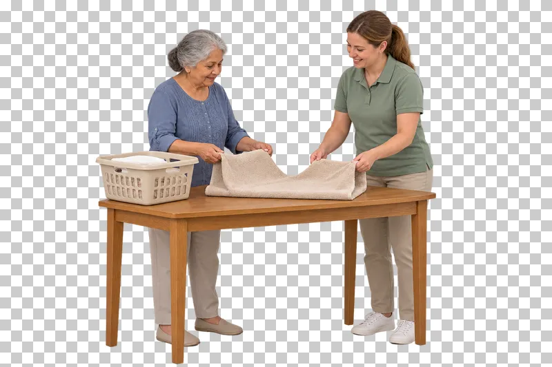 An older woman and a caregiver fold opposite ends of a towel at a compact table.