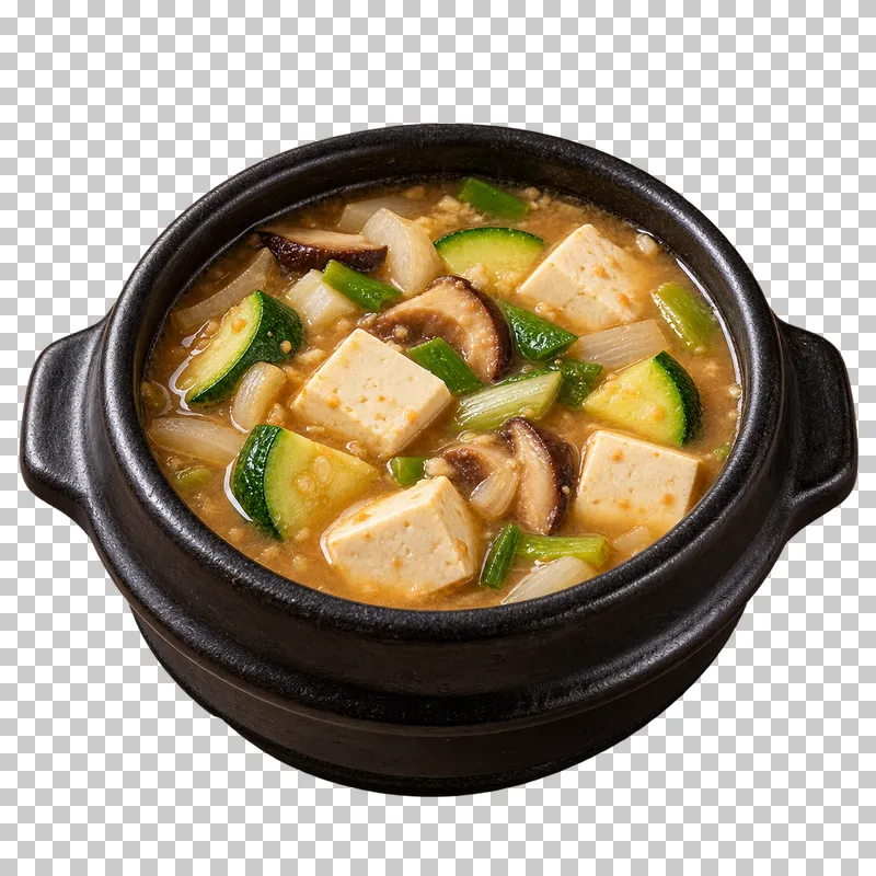 Doenjang-jjigae with firm tofu, zucchini, mushroom and onion in brown soybean-paste broth in a black pot.