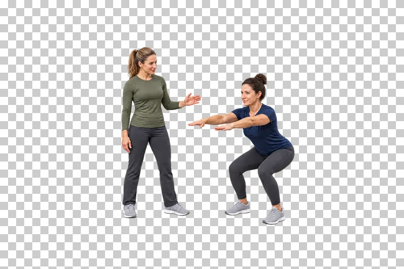 A female trainer giving an open-hand cue beside a woman holding a bodyweight squat.