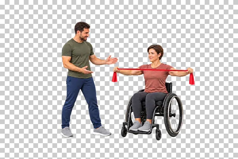 A woman in a manual wheelchair pulling a red band apart beside a standing trainer.